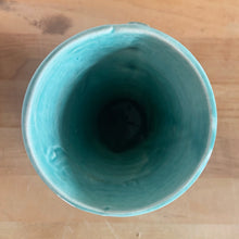 Load image into Gallery viewer, Vintage Art Deco gloss turquoise ring handled trumpet vase with leaves and berries on a ringed body. Crafted by McCoy Pottery, 1940s. This rare piece is must for any McCoy art pottery collector!

In as found vintage condition, no chips/repairs, tight hairline crack and crazing commensurate with age. Unmarked.

Measures 3 1/4 x 5 3/4 inches
