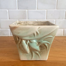 Load image into Gallery viewer, Vintage matte turquoise glazed lilies and leaves Rustic Line jardiniere planter. Crafted by McCoy Pottery, USA, 1945. This collectible planter is the perfect for succulents or decorative display and makes a lovely gift for an art pottery collector.

In excellent vintage condition, no chips,cracks or repairs, manufacturer&#39;s glaze pops. Unmarked.

Measures 4 5/8 x 4 1/8 x 4 inches
