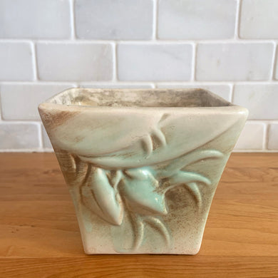 Vintage matte turquoise glazed lilies and leaves Rustic Line jardiniere planter. Crafted by McCoy Pottery, USA, 1945. This collectible planter is the perfect for succulents or decorative display and makes a lovely gift for an art pottery collector.

In excellent vintage condition, no chips,cracks or repairs, manufacturer's glaze pops. Unmarked.

Measures 4 5/8 x 4 1/8 x 4 inches