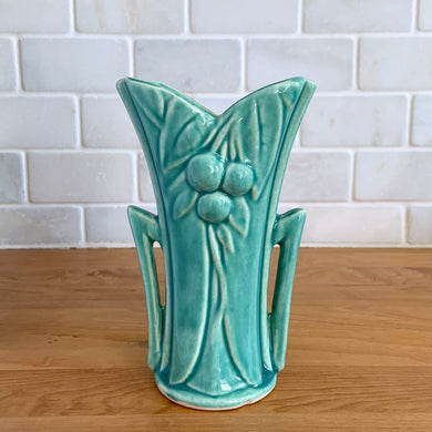 Vintage Art Deco turquoise split rim leaf and berries handled vase 104. Crafted by McCoy Pottery, 1948. This rare piece is must for any art pottery collector! A lovely way to enhance your home's decor or give as a gift!

In excellent vintage condition, no chips/cracks/repairs. Typical age-related crazing, manufacturer's glaze pops. Unmarked.

Measures 3 5/8 x 2 1/2 x 5 3/4 inches