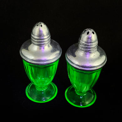 These antique vintage depression era art deco uranium glass miniature footed salt and pepper shakers featurings an eight panel design with metal lids. Produced in the USA, circa 1920s. This timeless kitchen accessory and their novel green uranium glass, which glows brilliantly under black light, adds a unique accent to your kitchen and table decor!  In excellent condition, free from chips. Minor wear to the lids.  Measures 1 1/ x 2 1/2 inches