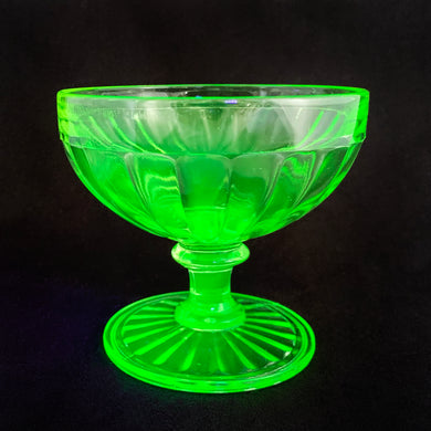 An antique vintage depression era uranium glass low sherbet or champagne glass with a ribbon pattern. Crafted by Hazel-Atlas Glass, USA, circa 1920s. This lovely piece of glass glows brilliantly under black light. This piece is the perfect as a dessert or champagne cup and could easily be repurposed to hold cotton balls or trinkets on a bath vanity/dresser.