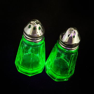 These antique vintage depression era panelled uranium glass  salt and pepper shakers with metal lids were produced by Hazel-Atlas Glass, USA, circa 1920s. This timeless kitchen accessory and their novel green uranium glass, which glows brilliantly under black light, adds a unique accent to your kitchen and table decor!  In excellent condition, free from chips. Wear to the lids.  Measures 1 3/8 x 2 7/8 inches