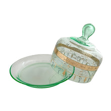 Load image into Gallery viewer, Antique Victorian era hand blown green uranium glass covered butter dish featuring gold, white and blue enamel decoration. Glows beautifully under black light. Crafted by Fenton Art Glass, USA, early 20th century. A stunning piece to add to your glass collection.

In as found vintage condition with wear to the enamel and chips to the dish rim and roughess to the lid rim.

Measures 7 1/8 x 7 1/8 x 5 1/2 inches

