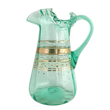 Load image into Gallery viewer, Antique Victorian era green uranium glass pitcher featuring gold, white and red enamel decoration with ruffle crimped rim and an applied handle. Glows beautifully under black light. Crafted by Fenton Art Glass, USA, early 20th century. A stunning piece to add to your glass collection.

In as found vintage condition with wear to the enamel. There is a stringer in the handle and a chip to the base of the handle itself.

Measures 5 3/4 x 8 x 10 inches
