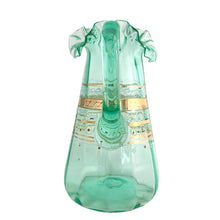 Load image into Gallery viewer, Antique Victorian era green uranium glass pitcher featuring gold, white and red enamel decoration with ruffle crimped rim and an applied handle. Glows beautifully under black light. Crafted by Fenton Art Glass, USA, early 20th century. A stunning piece to add to your glass collection.

In as found vintage condition with wear to the enamel. There is a stringer in the handle and a chip to the base of the handle itself.

Measures 5 3/4 x 8 x 10 inches
