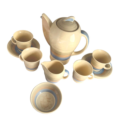 Vintage Art Deco style Wedding Ring coffee set in the blue, rust and gray colourway. Crafted by Susie Cooper, England, 1930s. This kestrel-shaped set comprised of a coffee pot with lid, creamer and sugar with four demitasse cups and saucers.

The set is in generally good vintage condition with no chips, cracks, or repairs. Each piece shows age-related crazing. The coffee pot has a chip at the top of the spout, and the sugar bowl has staining on the bottom. All pieces have maker's marks.