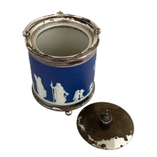 Load image into Gallery viewer, Three-quarter rear view of antique Wedgwood cobalt blue Jasperware biscuit barrel with silver-plated mounts, showing continuous neoclassical relief frieze and hinged lid

