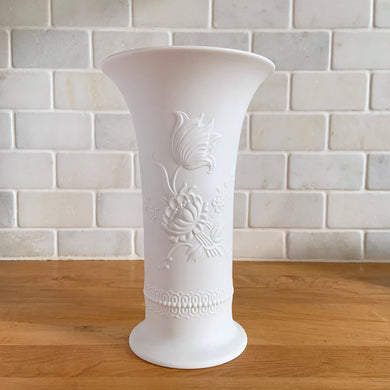 A delicate and elegant art nouveau style white bisque flower vase featuring embossed floral design and glazed on the inside. Marked 384/20. Crafted by Kaiser, Germany. In excellent condition, free from chips/cracks/repairs. Measures 5 x 8 inches
