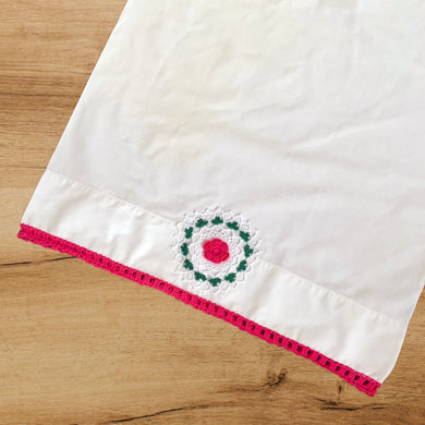 This single vintage white cotton pillowcase features a beautifully handcrafted crochet flower medallion and edge in deep pink, green and white. A gorgeous addition to your bed linens or repurpose for crafting! In excellent condition, free from tears or stains. Measures 32 x 20 inches