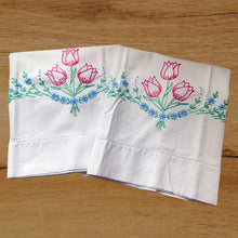 Load image into Gallery viewer, A lovely pair of vintage white cotton pillowcases, hand embroidered with a bouquet of raspberry pink tulips on green stems and a swag of blue flowers. A gorgeous addition to your bed linens!

In excellent condition, free from tears or stains.

Measures 30 3/4 x 18 inches
