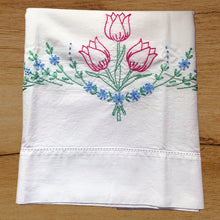 Load image into Gallery viewer, A lovely pair of vintage white cotton pillowcases, hand embroidered with a bouquet of raspberry pink tulips on green stems and a swag of blue flowers. A gorgeous addition to your bed linens!

In excellent condition, free from tears or stains.

Measures 30 3/4 x 18 inches
