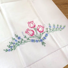 Load image into Gallery viewer, A lovely pair of vintage white cotton pillowcases, hand embroidered with a bouquet of raspberry pink tulips on green stems and a swag of blue flowers. A gorgeous addition to your bed linens!

In excellent condition, free from tears or stains.

Measures 30 3/4 x 18 inches
