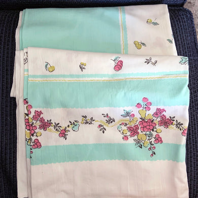 Give your table a vibrant, retro touch with this vintage white cotton tablecloth. Featuring fruits in eye-popping turquoise, pink, green, and black, it's sure to be the life of the party! Perfect for adding a hint of nostalgia to any gathering. Wow your guests!  In great vintage condition, free from tears. Minor stain.  Measures 65 x 46 inches