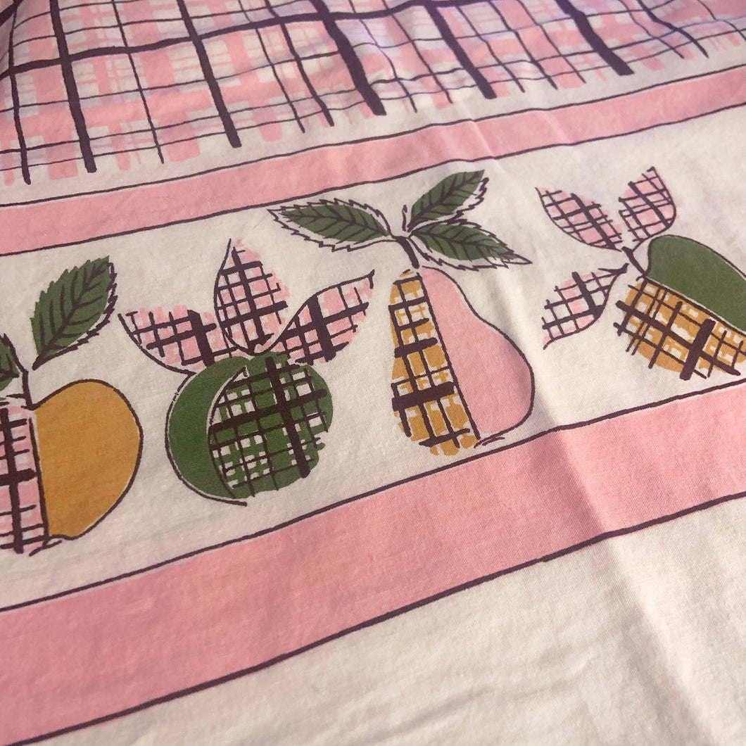 Vintage white cotton rectangular tablecloth featuring a central pink and brown offset gingham pattern bordered graphic fruits in pink ochre green and brown on either side of a pink band outlined in brown. Add vintage charm to your casual farmhouse, cottage or picnic table!

In good vintage condition, no tears. Stains to one edge, see photos.

Measures 45 x 64 inches