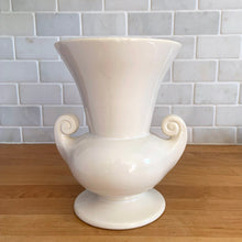 Load image into Gallery viewer, Vintage mid-century gloss white trumpet vase with curled handles. Crafted by McCoy Pottery, late 1950s. This lovely vase is must for any art pottery collector!

In as found vintage condition, chip to the exterior rim, no cracks/repairs, crazing commensurate with age. Maker&#39;s mark on the bottom.

Measures 6 1/4 x 5 7/8 x 8 inches
