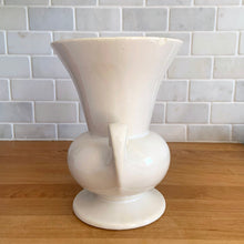 Load image into Gallery viewer, Vintage mid-century gloss white trumpet vase with curled handles. Crafted by McCoy Pottery, late 1950s. This lovely vase is must for any art pottery collector!

In as found vintage condition, chip to the exterior rim, no cracks/repairs, crazing commensurate with age. Maker&#39;s mark on the bottom.

Measures 6 1/4 x 5 7/8 x 8 inches
