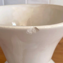 Load image into Gallery viewer, Vintage mid-century gloss white trumpet vase with curled handles. Crafted by McCoy Pottery, late 1950s. This lovely vase is must for any art pottery collector!

In as found vintage condition, chip to the exterior rim, no cracks/repairs, crazing commensurate with age. Maker&#39;s mark on the bottom.

Measures 6 1/4 x 5 7/8 x 8 inches
