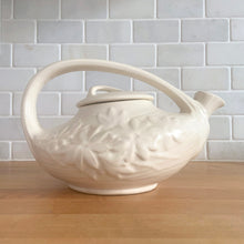 Load image into Gallery viewer, Gorgeous vintage Daisy teapot, glazed in matte white that displays beautifully. Crafted by McCoy Pottery, 1942. This rare teapot is must for any McCoy art pottery collector and a nice complement to your farmhouse, cottagecore and shabby chic decor!

In as found vintage condition, chip at the spout. Manufacturer&#39;s defects include a tight hairline crack at the under the spout that extends up the handle and typical glaze bubbles. No repairs. Maker&#39;s mark on the bottom.

Measures 9 3/4 x 6 1/4 x 6 1/4 inches
