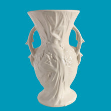 Load image into Gallery viewer, Beautiful vintage Bird of Paradise vase glazed in gloss white, features embossed bird and botanicals. Crafted by McCoy Pottery, 1940s. This vase is must for any art pottery collector!

In vintage condition, no repairs, chip on the foot. There is crazing present and one of the lines penetrates both sides at the rim, and appears stable. Maker&#39;s mark on the bottom.

Measures 4 7/8 x 3 3/4 x 8 inches
