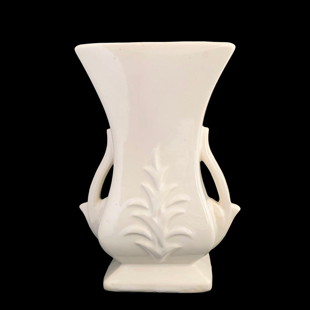 Beautiful vintage gloss white handled vase, features embossed fern. Crafted by McCoy Pottery, late 1940s. This vase is must for any art pottery collector!

In excellent vintage condition, minor spot of roughness to the rim along with age-related crazing. Maker's mark on the bottom.

Measures 5 1/2 x 3 5/8 x 8 1/8 inches