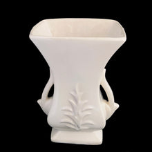 Load image into Gallery viewer, Beautiful vintage gloss white handled vase, features embossed fern. Crafted by McCoy Pottery, late 1940s. This vase is must for any art pottery collector!

In excellent vintage condition, minor spot of roughness to the rim along with age-related crazing. Maker&#39;s mark on the bottom.

Measures 5 1/2 x 3 5/8 x 8 1/8 inches
