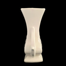 Load image into Gallery viewer, Beautiful vintage gloss white handled vase, features embossed fern. Crafted by McCoy Pottery, late 1940s. This vase is must for any art pottery collector!

In excellent vintage condition, minor spot of roughness to the rim along with age-related crazing. Maker&#39;s mark on the bottom.

Measures 5 1/2 x 3 5/8 x 8 1/8 inches
