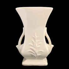 Load image into Gallery viewer, Beautiful vintage gloss white handled vase, features embossed fern. Crafted by McCoy Pottery, late 1940s. This vase is must for any art pottery collector!

In excellent vintage condition, minor spot of roughness to the rim along with age-related crazing. Maker&#39;s mark on the bottom.

Measures 5 1/2 x 3 5/8 x 8 1/8 inches
