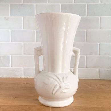 Vintage Art Deco gloss white handled trumpet vase with embossed flowers. Crafted by McCoy Pottery, 1950s. This rare piece is must for any McCoy art pottery collector!

In excellent vintage condition, no chips/cracks/repairs. Maker's mark.

Measures 4 1/4 x 8 1/8 inches