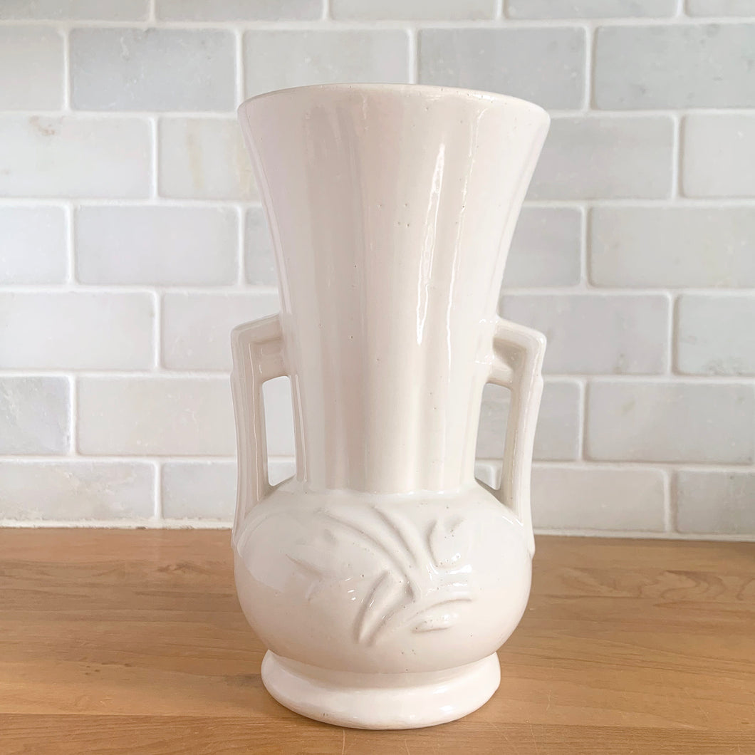 Vintage Art Deco gloss white handled trumpet vase with embossed flowers. Crafted by McCoy Pottery, 1950s. This rare piece is must for any McCoy art pottery collector!

In excellent vintage condition, no chips/cracks/repairs. Maker's mark.

Measures 4 1/4 x 8 1/8 inches