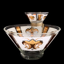 Load image into Gallery viewer, Vintage chip and dip set featuring a white and gold Fleurs-de-lis motif on glass. The set consists of a large main chip bowl and a smaller dip bowl that attaches via a metal gold-toned bracket. Crafted by Anchor Hocking, 1960s. The retro way to serve your favourite snacks at your next party, movie or game night.
