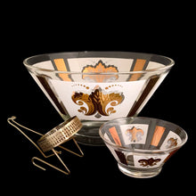 Load image into Gallery viewer, Vintage chip and dip set featuring a white and gold Fleurs-de-lis motif on glass. The set consists of a large main chip bowl and a smaller dip bowl that attaches via a metal gold-toned bracket. Crafted by Anchor Hocking, 1960s. The retro way to serve your favourite snacks at your next party, movie or game night.

