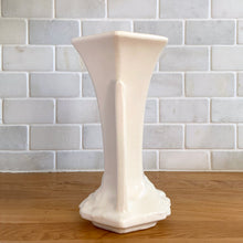 Load image into Gallery viewer, Vintage Art Deco matte white trumpet vase features a unique stretch hexagonal shape and asymmetric handles with leaf and berry motif. Crafted by Nelson McCoy Pottery, 1940s. This rare piece is must for any art pottery collector! A lovely way to enhance your home&#39;s decor or give as a gift!

In excellent vintage condition, no chips/cracks/repairs. Typical age-related crazing, manufacturer&#39;s glaze pops. Maker&#39;s mark.

Measures 5 1/2 x 4 1/4 x 8 inches
