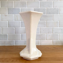 Load image into Gallery viewer, Vintage Art Deco matte white trumpet vase features a unique stretch hexagonal shape and asymmetric handles with leaf and berry motif. Crafted by Nelson McCoy Pottery, 1940s. This rare piece is must for any art pottery collector! A lovely way to enhance your home&#39;s decor or give as a gift!

In excellent vintage condition, no chips/cracks/repairs. Typical age-related crazing, manufacturer&#39;s glaze pops. Maker&#39;s mark.

Measures 5 1/2 x 4 1/4 x 8 inches
