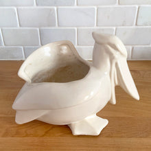 Load image into Gallery viewer, Vintage mid-century era matte white Pelican pattern planter. Crafted by Nelson McCoy Pottery, 1948. Perfect as a succulent planter or to hold baby accessories as part of your nursery decor! This rare piece is must for any art pottery collector.

In excellent vintage condition, no chips/cracks/repairs, age-related crazing and interior staining. Manufacturer's glaze pops. Maker's mark.

Measures 7 3/4 x 4 1/4 x 5 1/2 inches
