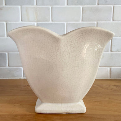 Vintage white tulip vase. Crafted by McCoy Pottery, USA, 1940s. This collectible vase is the perfect for a charming floral bouquet and makes a lovely gift for an art pottery collector.

In as found vintage condition, chip to the underside of the foot, significant age-related crazing, tight hairline crack, manufacturer's glaze pops. Maker's mark.

Measures 7 1/2 x 3 3/4 x 6 1/8 inches