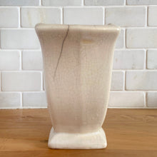 Load image into Gallery viewer, Vintage white tulip vase. Crafted by McCoy Pottery, USA, 1940s. This collectible vase is the perfect for a charming floral bouquet and makes a lovely gift for an art pottery collector.

In as found vintage condition, chip to the underside of the foot, significant age-related crazing, tight hairline crack, manufacturer&#39;s glaze pops. Maker&#39;s mark.

Measures 7 1/2 x 3 3/4 x 6 1/8 inches
