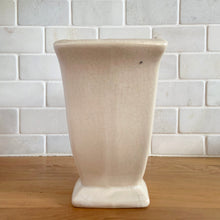 Load image into Gallery viewer, Vintage white tulip vase. Crafted by McCoy Pottery, USA, 1940s. This collectible vase is the perfect for a charming floral bouquet and makes a lovely gift for an art pottery collector.

In as found vintage condition, chip to the underside of the foot, significant age-related crazing, tight hairline crack, manufacturer&#39;s glaze pops. Maker&#39;s mark.

Measures 7 1/2 x 3 3/4 x 6 1/8 inches
