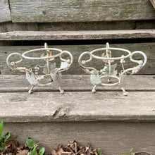 Load image into Gallery viewer, Pair of white vintage mid-century era shabby chic wrought iron metal garden plant stands decorated with grapevines. Includes pink plastic pot inserts. Perfect for your favourite plants.

In as found vintage condition.

Plant stands measure 6 1/2 x 5 1/2 inches

Plastic pots measure 4 3/8 x 3 3/4 inches

