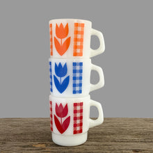 Load image into Gallery viewer, Vintage milk glass mug with vibrant tulip flowers and gingham check bands. Choose from red, orange or blue. Crafted by Termoscrisa Glass, Mexico. Circa 1980s. Perfect for your cuppa Joe!  In excellent condition, no chips/wear.  Measures 3 x 3 3/8 inches  Capacity 8 ounces
