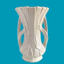 Load image into Gallery viewer, Vintage shiny white glazed ribbon strap vase with double handles. Crafted by McCoy Pottery, 1940s. A must for any art pottery collector!

In excellent condition, no chips, no cracks, no repairs and no visible crazing which is incredible for a piece of this age. Maker&#39;s mark on the bottom.

Measures 7 3/4 x 12 inches
