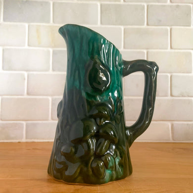 This gorgeous Evangeline pitcher features a stunning design of raised mushrooms and knots around a tree trunk. This sweet pitcher makes for a beautiful statement piece or a functional pitcher for your home.  In excellent condition, free from chips/cracks.  Measures 3 3/4 x 6 3/8 inches