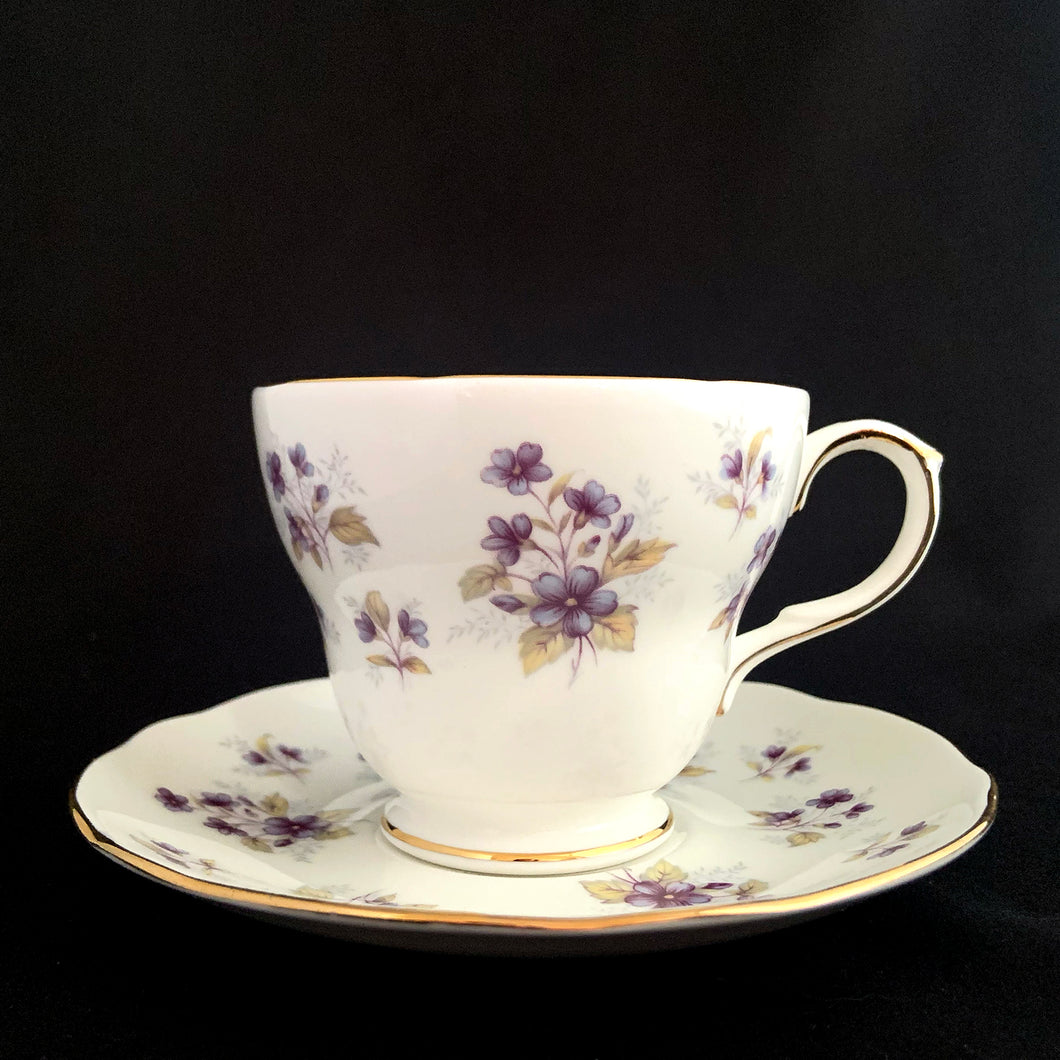 Vintage Woodside white bone china teacup and saucer features purple violets, trimmed in gold gilt. Crafted by Duchess, England, 1960s. A lovely way to enjoy a cuppa tea!

In excellent condition, no chips, cracks or repairs. Maker's mark on the bottom.

Measures 3 7/8 x 2 3/4 x 5 1/2 inches