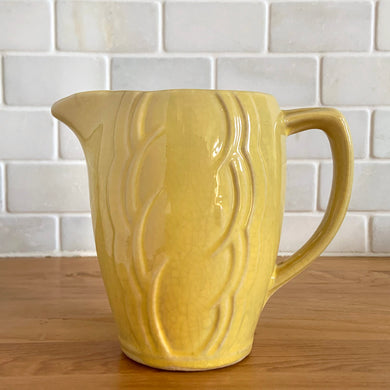 Charming vintage sunny yellow milk pitcher featuring embossed vertical scalloped pattern. Crafted by McCoy Pottery, 1964. This collectible pitcher is the perfect vessels to hold a charming bouquet of spring flowers or a lovely gift for an art pottery collector.

In vintage condition, no chips/cracks/repairs, age-related crazing and staining, manufacturer's glaze pops. Maker's mark.

Measures 6 x 3 1/2 x 5 1/8 inches