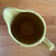 Load image into Gallery viewer, Charming vintage sunny yellow milk pitcher featuring embossed vertical scalloped pattern. Crafted by McCoy Pottery, 1964. This collectible pitcher is the perfect vessels to hold a charming bouquet of spring flowers or a lovely gift for an art pottery collector.

In vintage condition, no chips/cracks/repairs, age-related crazing and staining, manufacturer&#39;s glaze pops. Maker&#39;s mark.

Measures 6 x 3 1/2 x 5 1/8 inches
