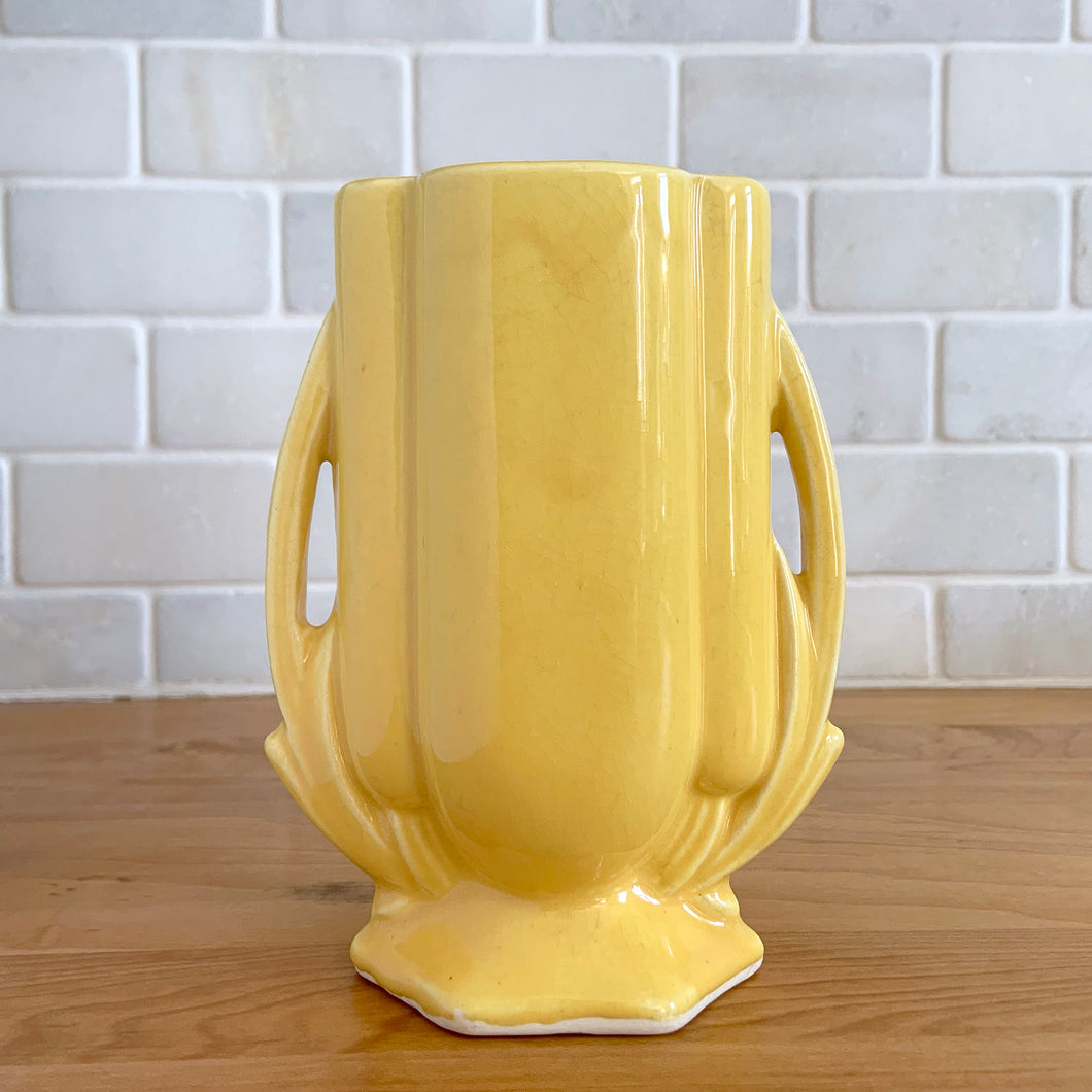 Vintage Art Deco yellow vase features a unique shape and double leaf decorative handles, 105. Crafted by McCoy Pottery, 1940s. This rare piece is must for any art pottery collector! A lovely way to enhance your home's decor or give as a gift!

In excellent vintage condition, no chips/cracks/repairs. Typical age-related crazing, manufacturer's glaze pops. Unmarked.

Measures 4 x 2 1/8 x 5 1/2 inches