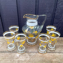 Load image into Gallery viewer, Vintage blown glass lemonade pitcher and glasses set hand painted with yellow flowers with gold leaves, white and gold bands and rims. Crafted in Romania, 1950s. A lovely set to add cheer to your table.

In excellent condition, no chips. Original stickers marked, Made in Roumania.

Pitcher measures 8 1/2 x 11 inches. Capacity 80 ounces

Glasses measure 3 1/2 x 5 7/8 inches. Capacity 16 ounces

