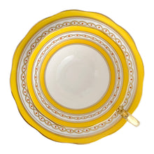 Load image into Gallery viewer, This antique bone china footed teacup and saucer is so sweet! Both the cup and saucer have a lovely scalloped edge, hand painted gold gilt bands over yellow and white glazed porcelain and a gold gilt infinity ribbon dotted in orange. Produced by Royal Albert Crown China, England. Based on the maker&#39;s mark, dates to 1927 - 1935.  In excellent condition, free from chips, cracks or repairs. Maker&#39;s mark on the bottom of both pieces. Teacup is marked with the number 591. 
