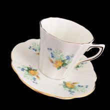 Load image into Gallery viewer, A lovely vintage white bone china scalloped shaped teacup and saucer featuring yellow roses and blue flowers. Crafted by Montrose, England, circa 1970s. The perfect vessel for an excellent cuppa tea!

In excellent condition, no chips, cracks or repairs. Maker&#39;s marks on the bottom.

Teacup measures 3 x 2 7/8 inches | Saucer measures 5 1/2 inches
