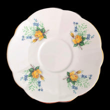 Load image into Gallery viewer, A lovely vintage white bone china scalloped shaped teacup and saucer featuring yellow roses and blue flowers. Crafted by Montrose, England, circa 1970s. The perfect vessel for an excellent cuppa tea!

In excellent condition, no chips, cracks or repairs. Maker&#39;s marks on the bottom.

Teacup measures 3 x 2 7/8 inches | Saucer measures 5 1/2 inches
